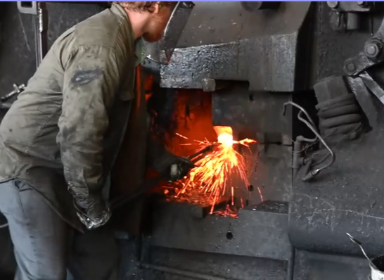 A Warwood Tool forge worker shaping heated steel beneath a forging hammer